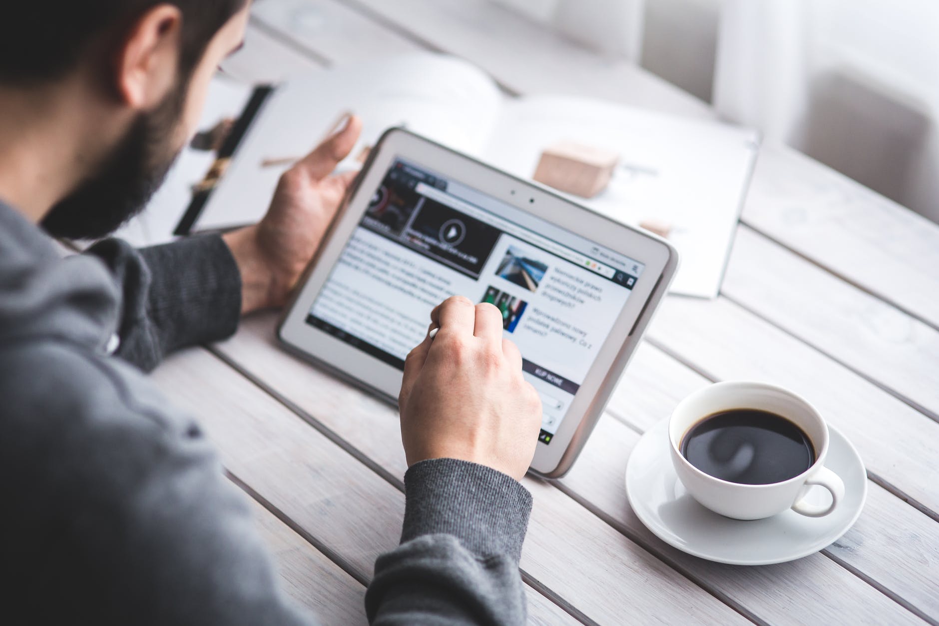 A man searching the web on his tablet with some coffee 